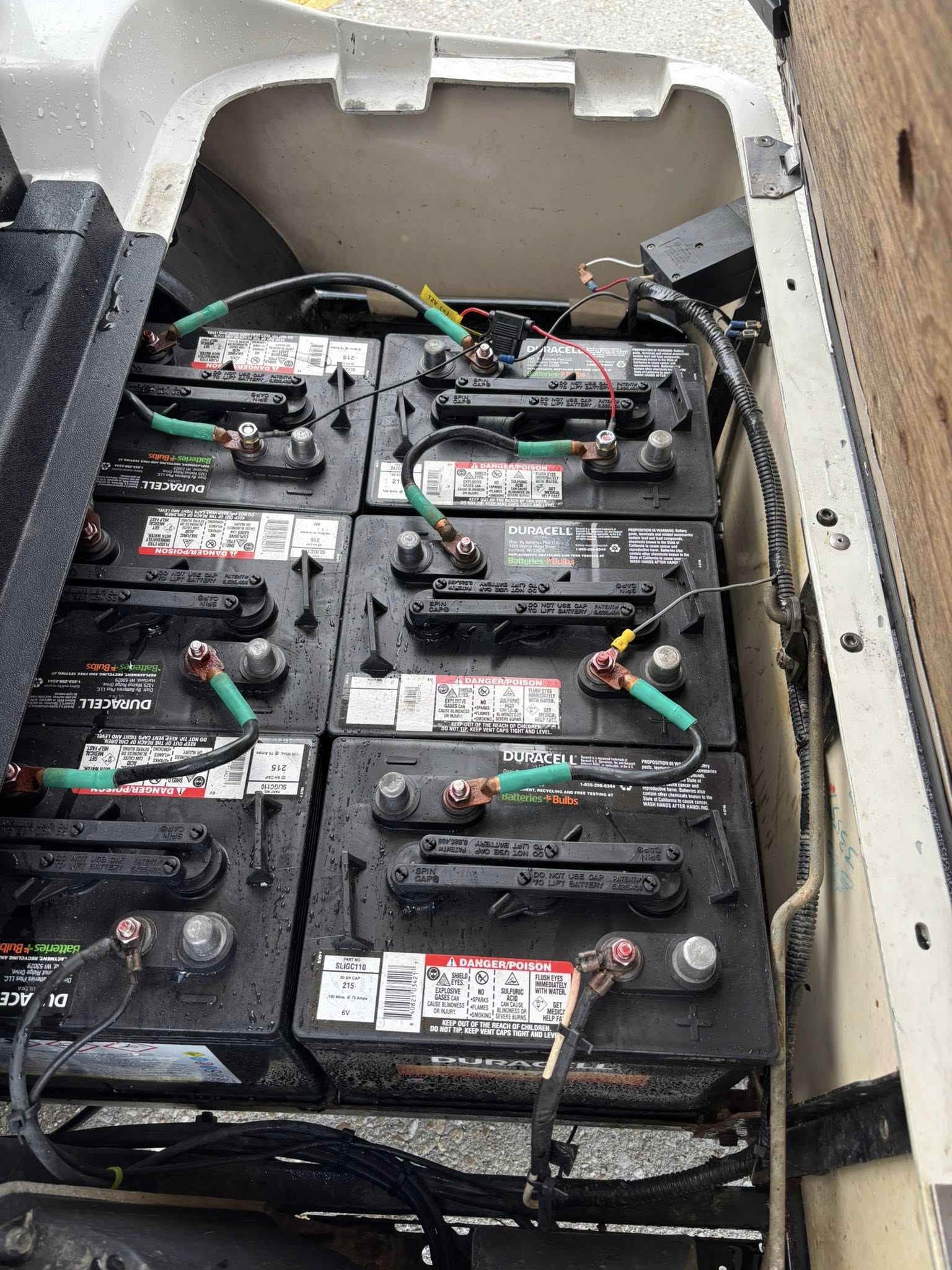 Battery compartment of an electric golf cart showing multiple installed batteries and wiring connections.